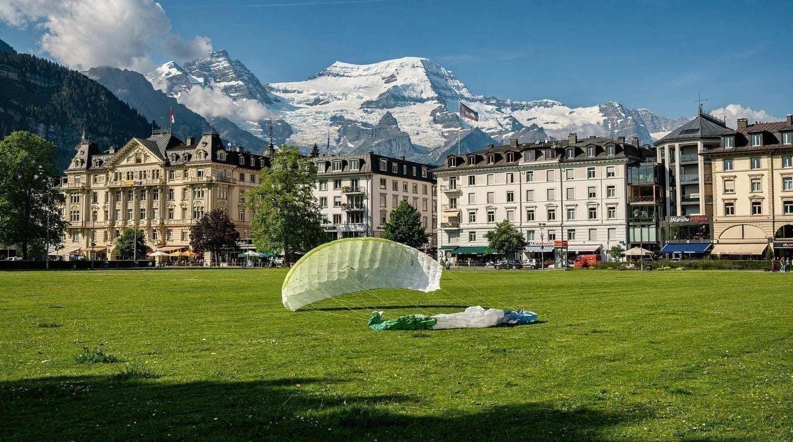 Der Höheweg und die Höhematte in Interlaken in der Abenddämmerung, mit den Alpen am Horizont.